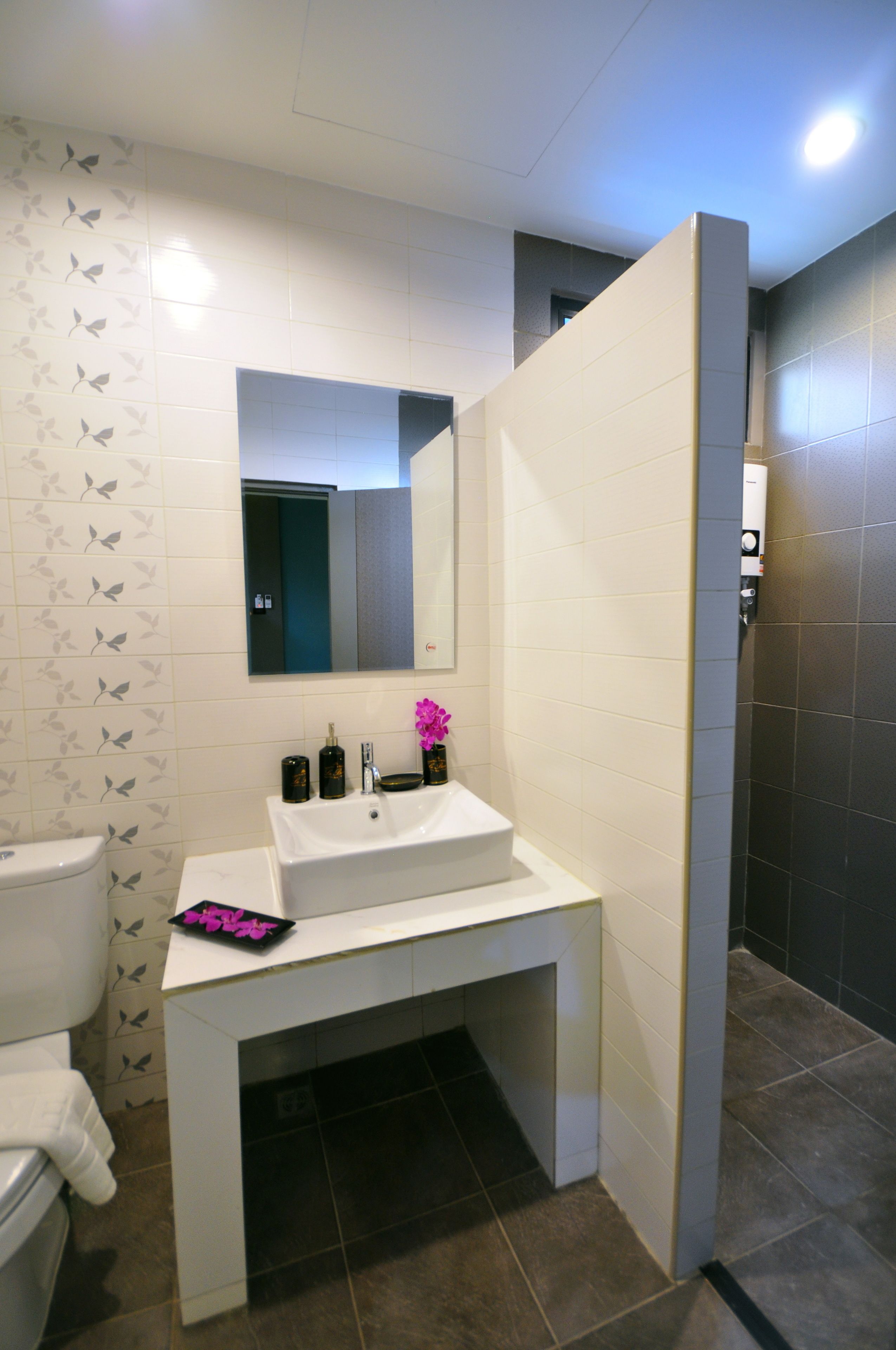 Un baño moderno con lavamanos, espejo y retrete blancos.