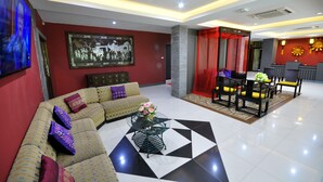 A modern hotel lobby with a sectional sofa, a glass coffee table, and a dining area with chairs and a table. - Chiangmai SP Hotel (Chiang Mai)