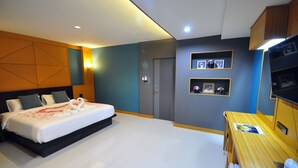 A modern hotel room with a large bed, a wooden desk, and built-in shelving with framed photos. - Chiangmai SP Hotel (Chiang Mai)