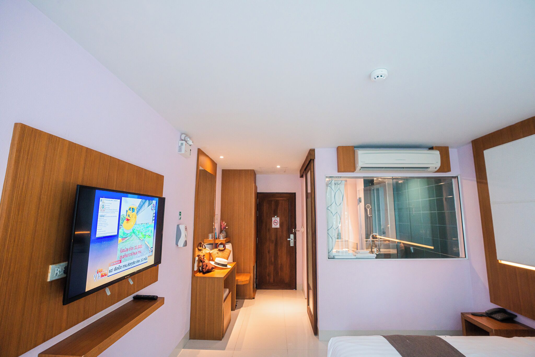 Habitación de hotel con televisión, escritorio con silla, ventana con vistas y baño con ducha y lavamanos.