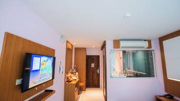 Habitación de hotel con televisión, escritorio con silla, ventana con vistas y baño con ducha y lavamanos.