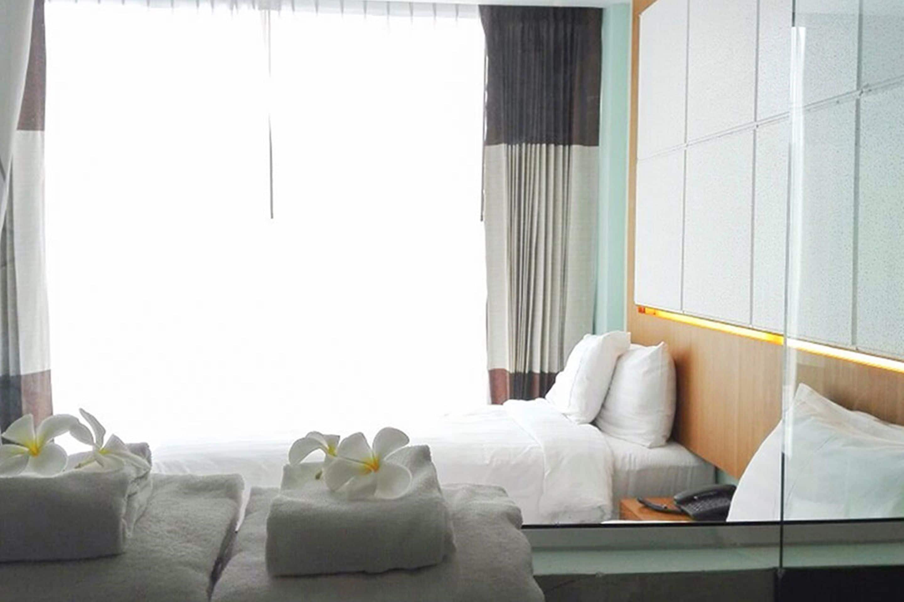 Habitación de hotel con cama, mesita de noche y espejo que refleja el cuarto.