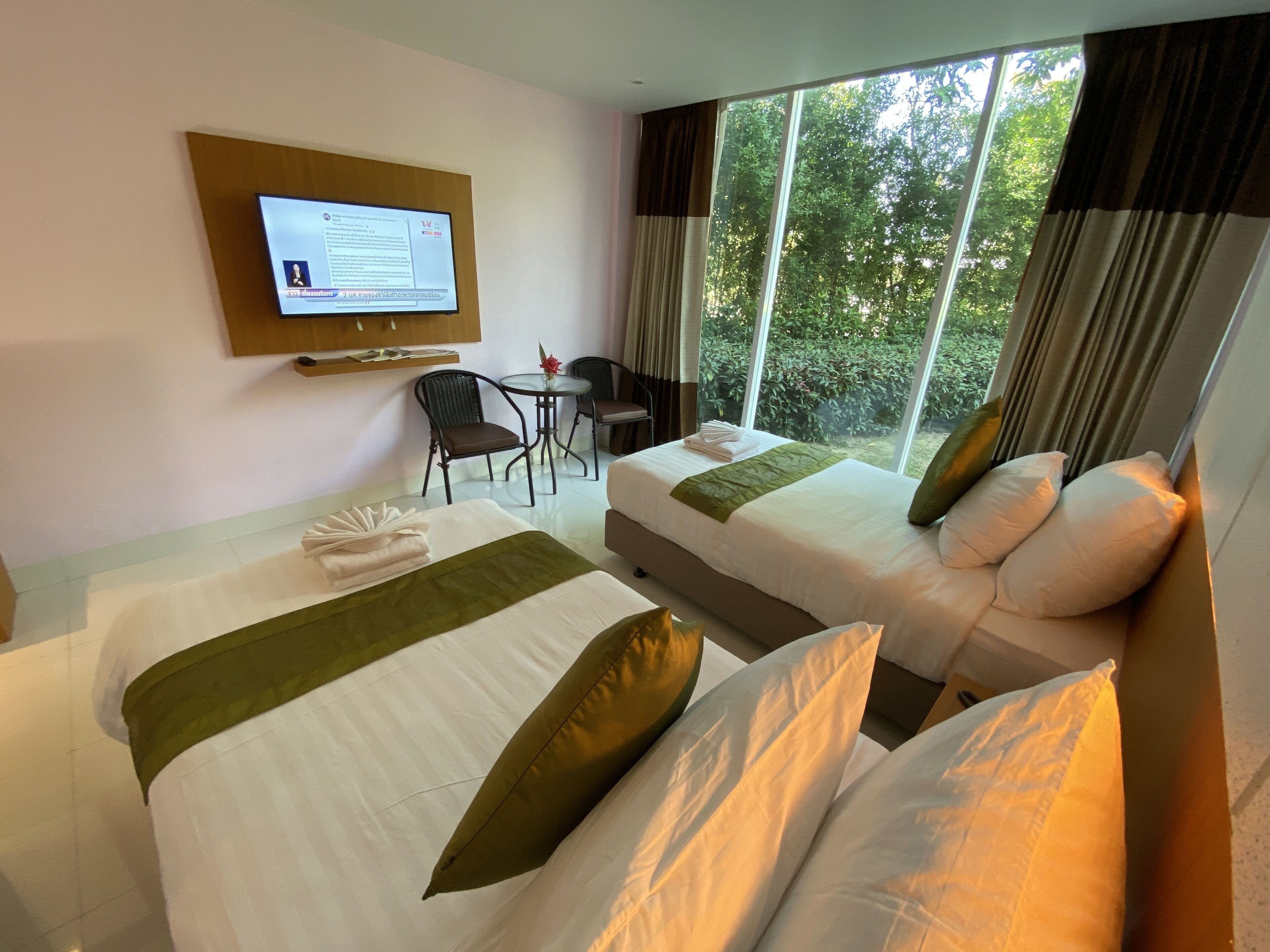 A hotel room with two beds, a desk, a chair, and a TV mounted on the wall.