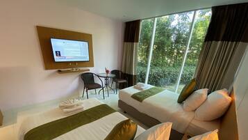 A hotel room with two beds, a desk, a chair, and a TV mounted on the wall.