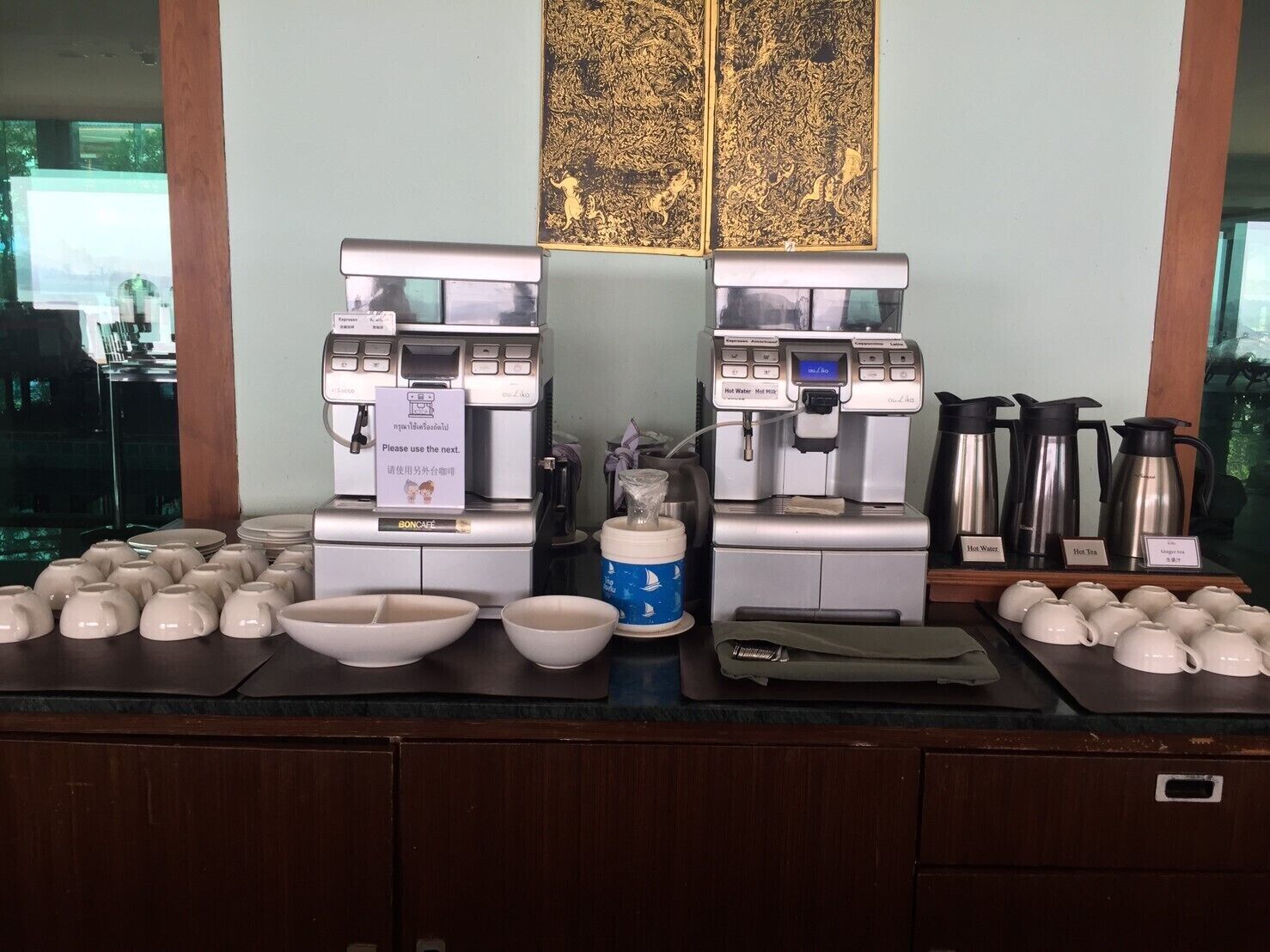 Eine Kaffeestation mit zwei Espressomaschinen, einem Kaffeekannen und mehreren Einwegbechern.