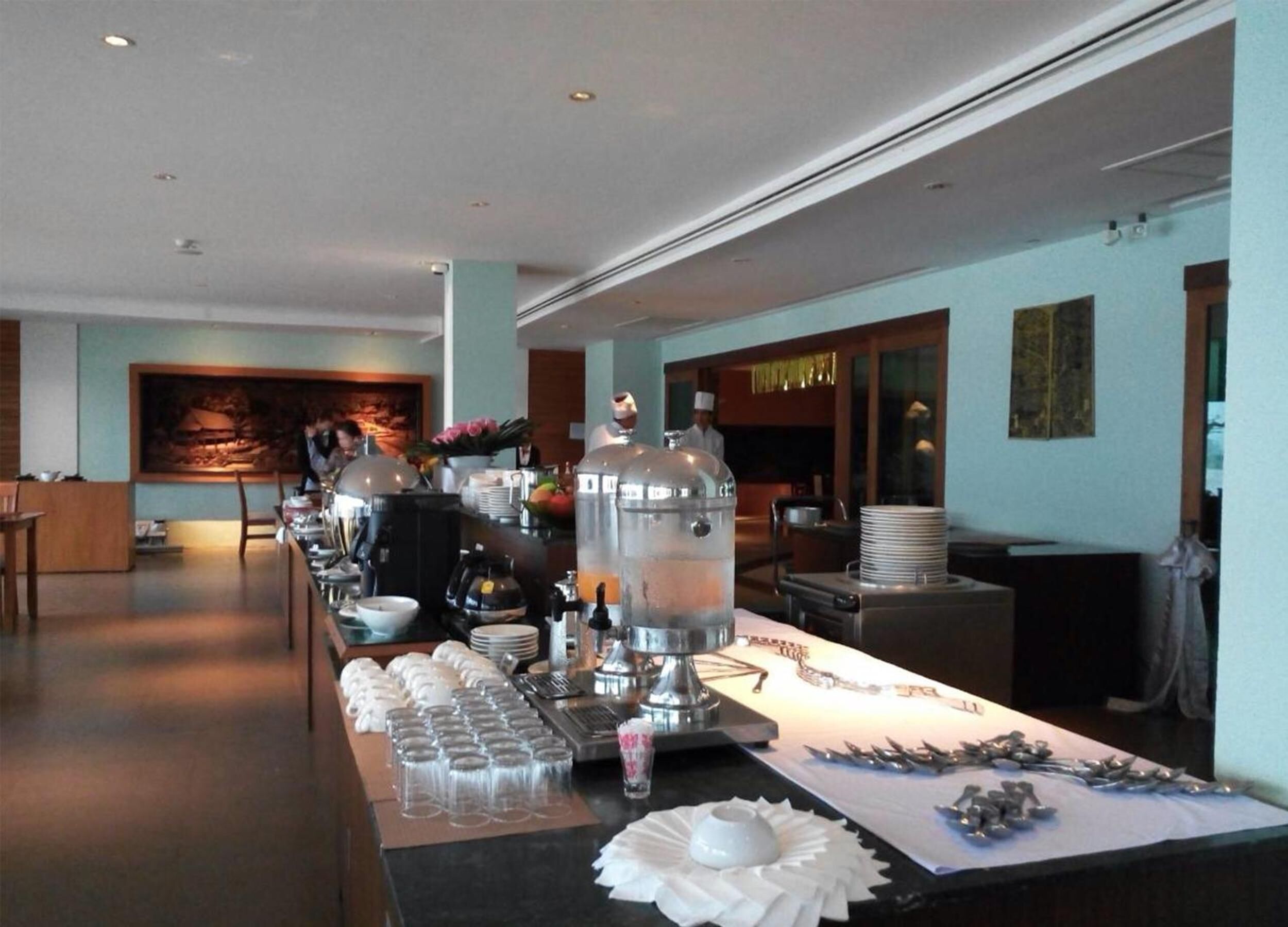A buffet setup with a long counter, various food items, and a chef in the background.