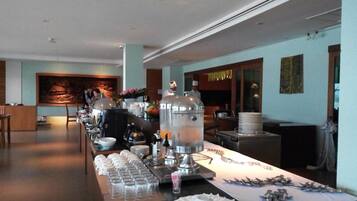 A buffet setup with a long counter, various food items, and a chef in the background.