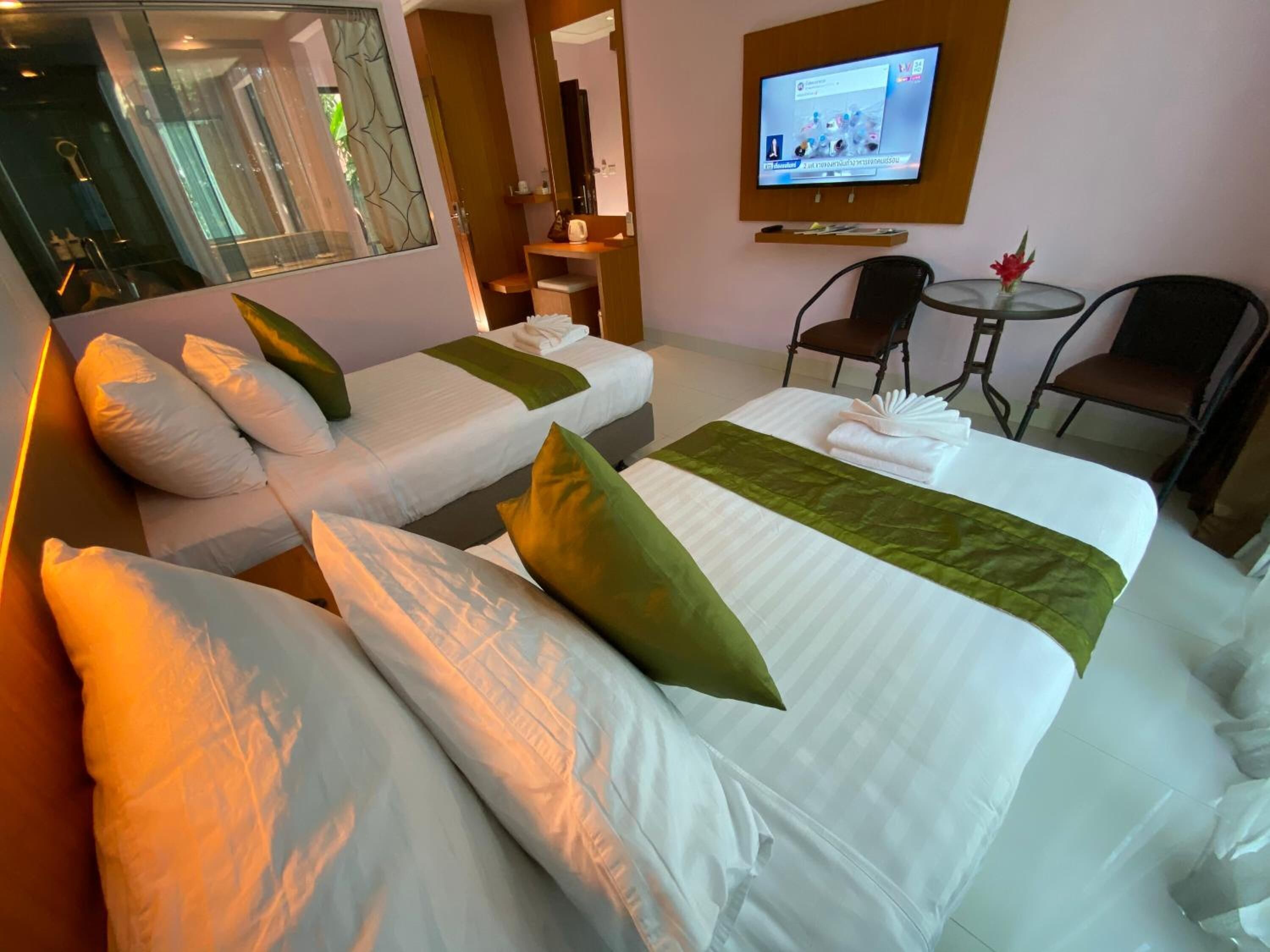 A hotel room with two beds, a TV, a small table, and chairs.