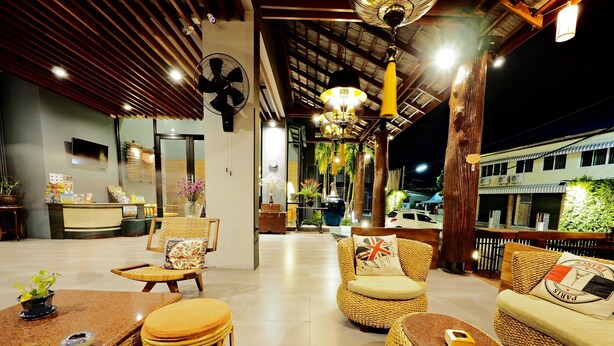 A well-lit outdoor seating area with wicker furniture, a reception desk, and a fan. - Le Naview @Prasingh (Chiang Mai)