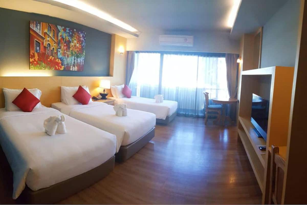 Una habitación de hotel con tres camas, televisión y un cuadro en la pared.