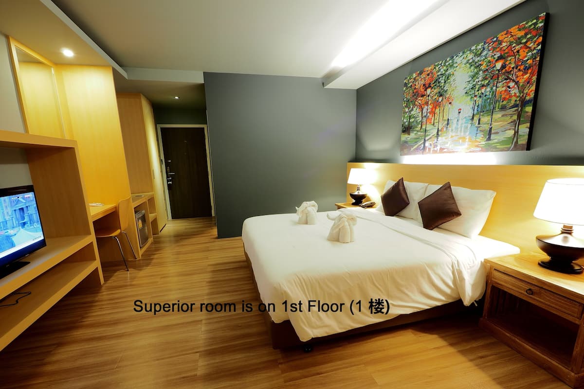 Habitación de hotel con cama, mesitas de noche, televisor y un cuadro en la pared.