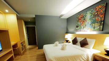 A hotel room with a bed, bedside table, lamp, and a painting on the wall.
