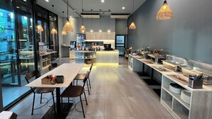 A modern restaurant with a long counter, multiple seating areas, and a kitchen visible in the background. - Le Naview @Prasingh (Chiang Mai)