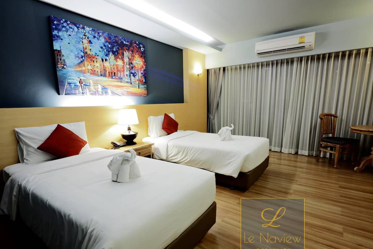 Habitación de hotel con dos camas, un cuadro en la pared, aire acondicionado y piso de madera.