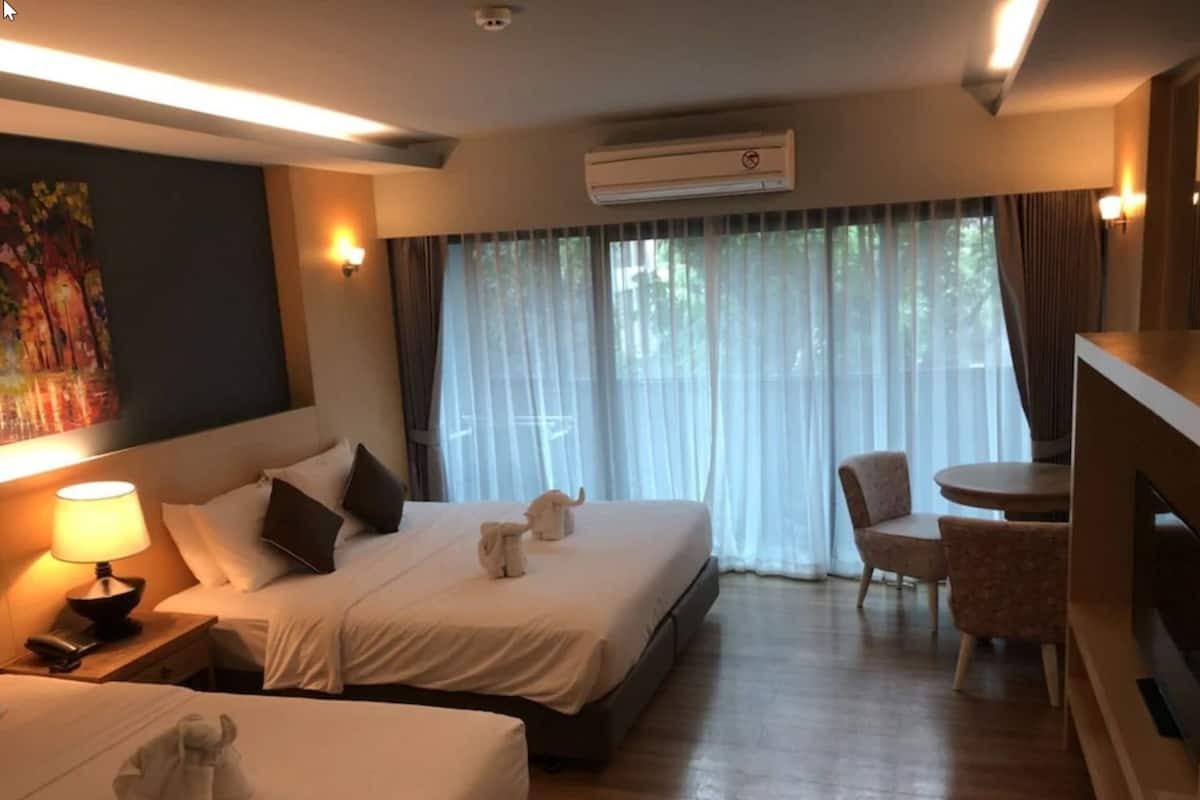 Una habitación de hotel con dos camas, un escritorio, una silla y un televisor.