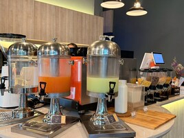 Una estación de bebidas con dispensadores, una máquina de café y un terminal de pago digital.