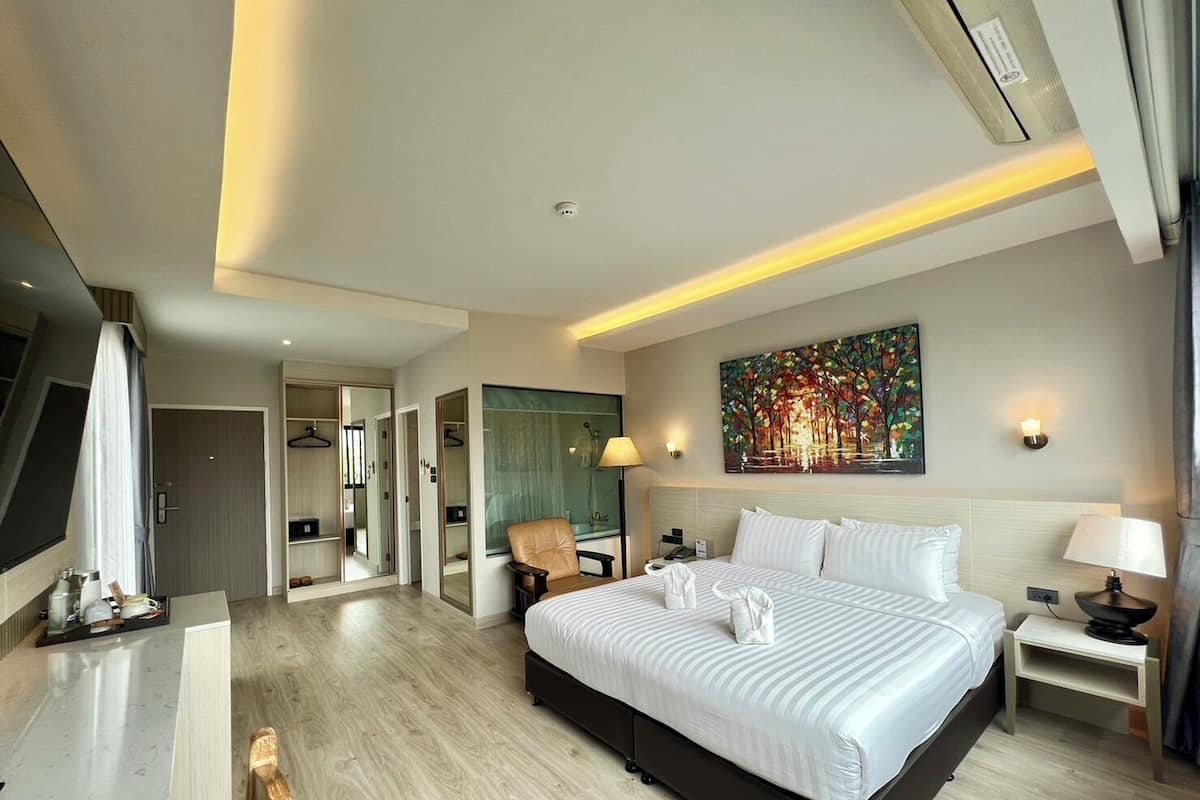 Una habitación de hotel moderna con una cama grande, un escritorio, una silla y un cuadro en la pared.