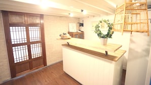 A reception area with a wooden counter, a potted plant, and a traditional Japanese sliding door. - Blue Jasmine Hostel (Bangkok)