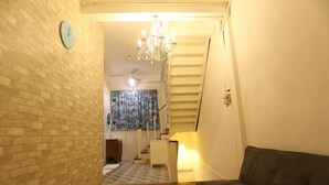 A staircase leading to a second floor, a chandelier, a clock, and a patterned rug. - Blue Jasmine Hostel (Bangkok)