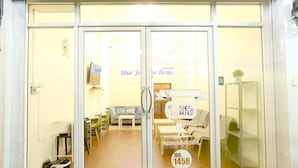 A hotel entrance with a reception desk, seating area, and a sign indicating room availability. - Blue Jasmine Hostel (Bangkok)