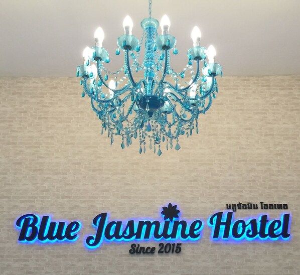 Un candelabro con múltiples luces y un letrero de neón para el Hostal Blue Jasmine.