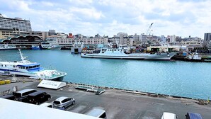 A harbor with several ships docked, a marina with boats, and a cityscape in the background. - My Place - Hostel (Naha)