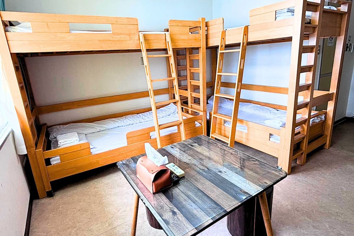 Un dormitorio con literas, una mesa de madera y un cesto de basura.