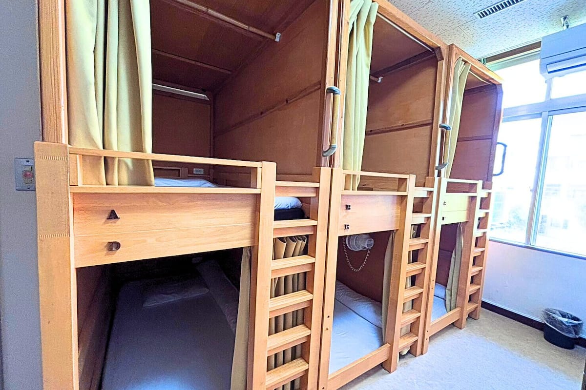 Una habitación con dos camas literas de madera, cada una con escritorio y cajones.