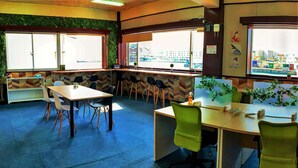 A conference room with a large window, a green plant, and a city view. - My Place - Hostel (Naha)