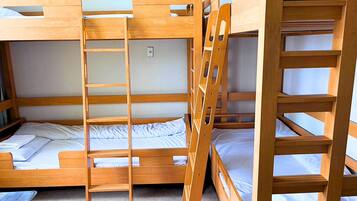 A bunk bed room with a ladder, wooden headboard, and a small table.
