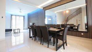 Un comedor moderno con un espejo grande, una mesa de comedor con sillas y una escalera al fondo.