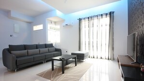 Una sala de estar moderna con sofá, mesa de centro y televisor de pantalla plana.