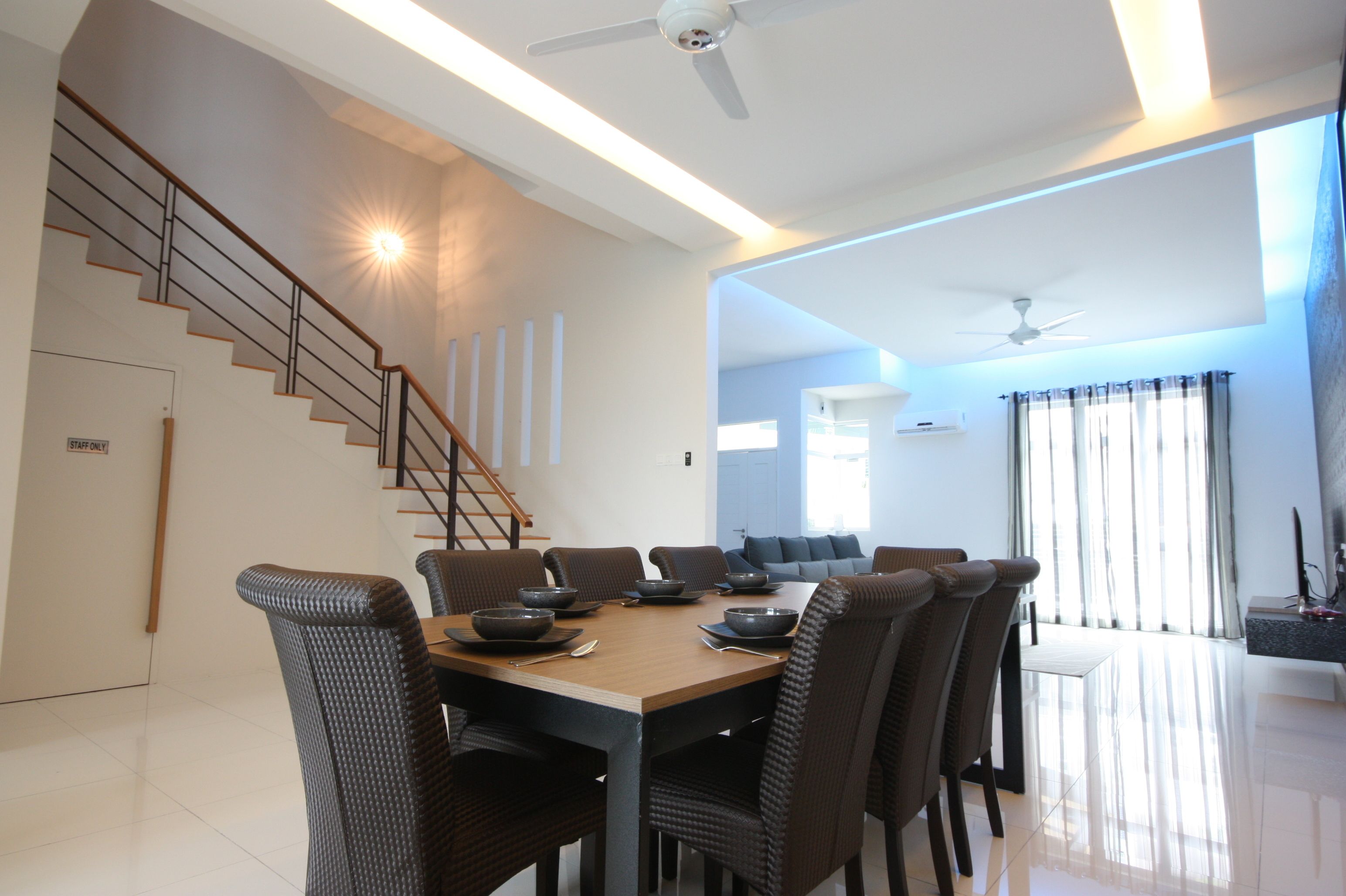 A modern dining area with a wooden table, dark chairs, and a staircase leading to another level.