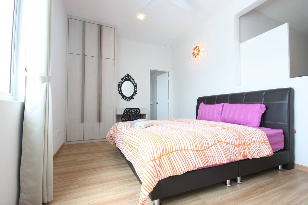 A bedroom with a bed, a wardrobe, a mirror, and a light fixture.