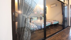 Un dormitorio moderno con dos camas, un cristalero corredero y vista a una escalera.