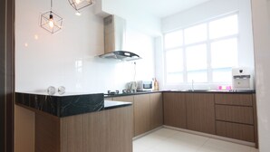 Una cocina moderna con armarios de madera, encimera de mármol e iluminación colgante.