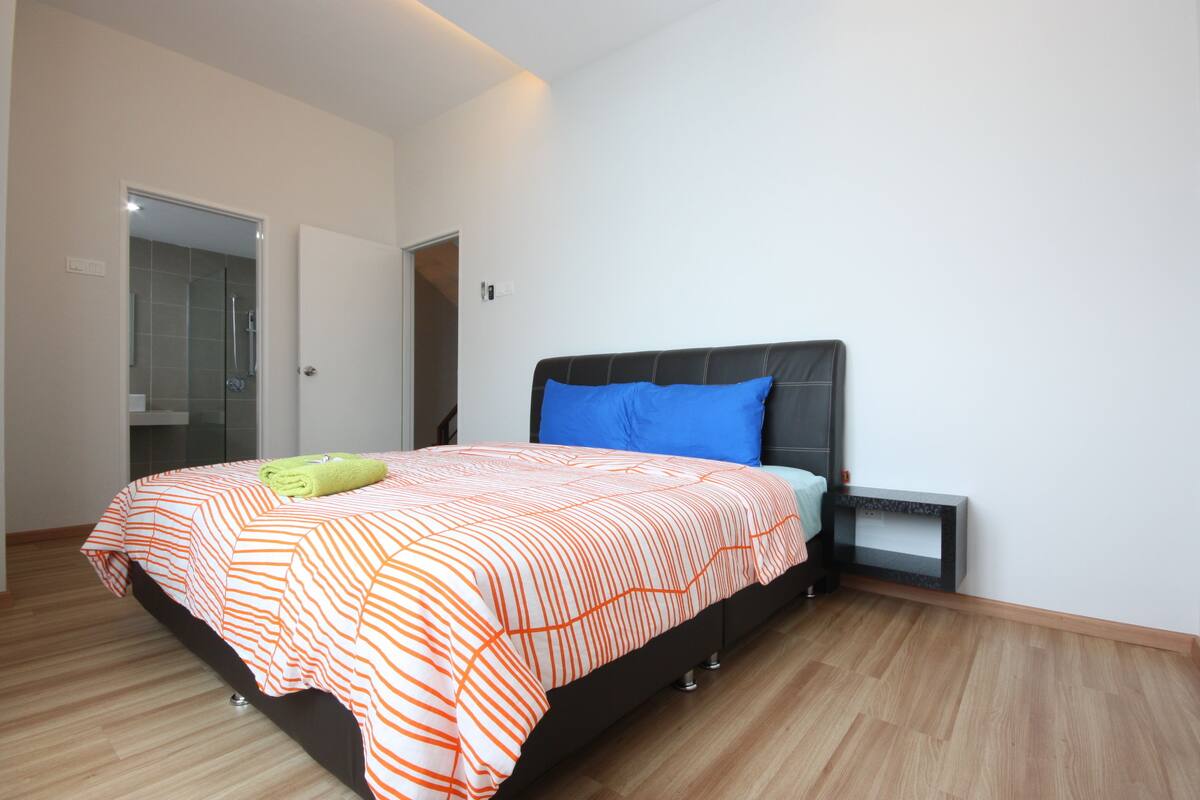 A bedroom with a bed, a nightstand, and a door leading to a bathroom.
