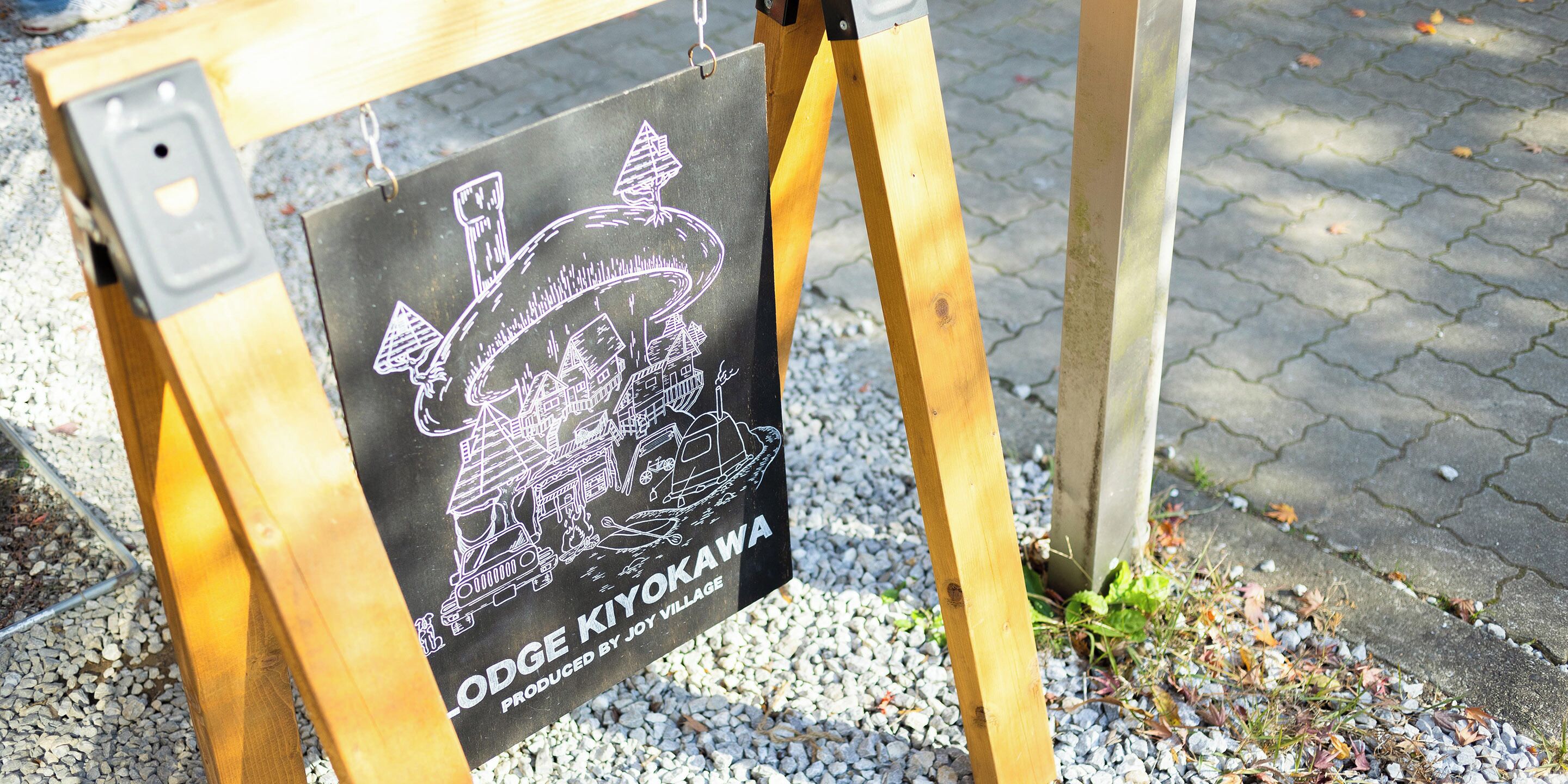 A wooden easel with a black sign featuring a drawing and text.