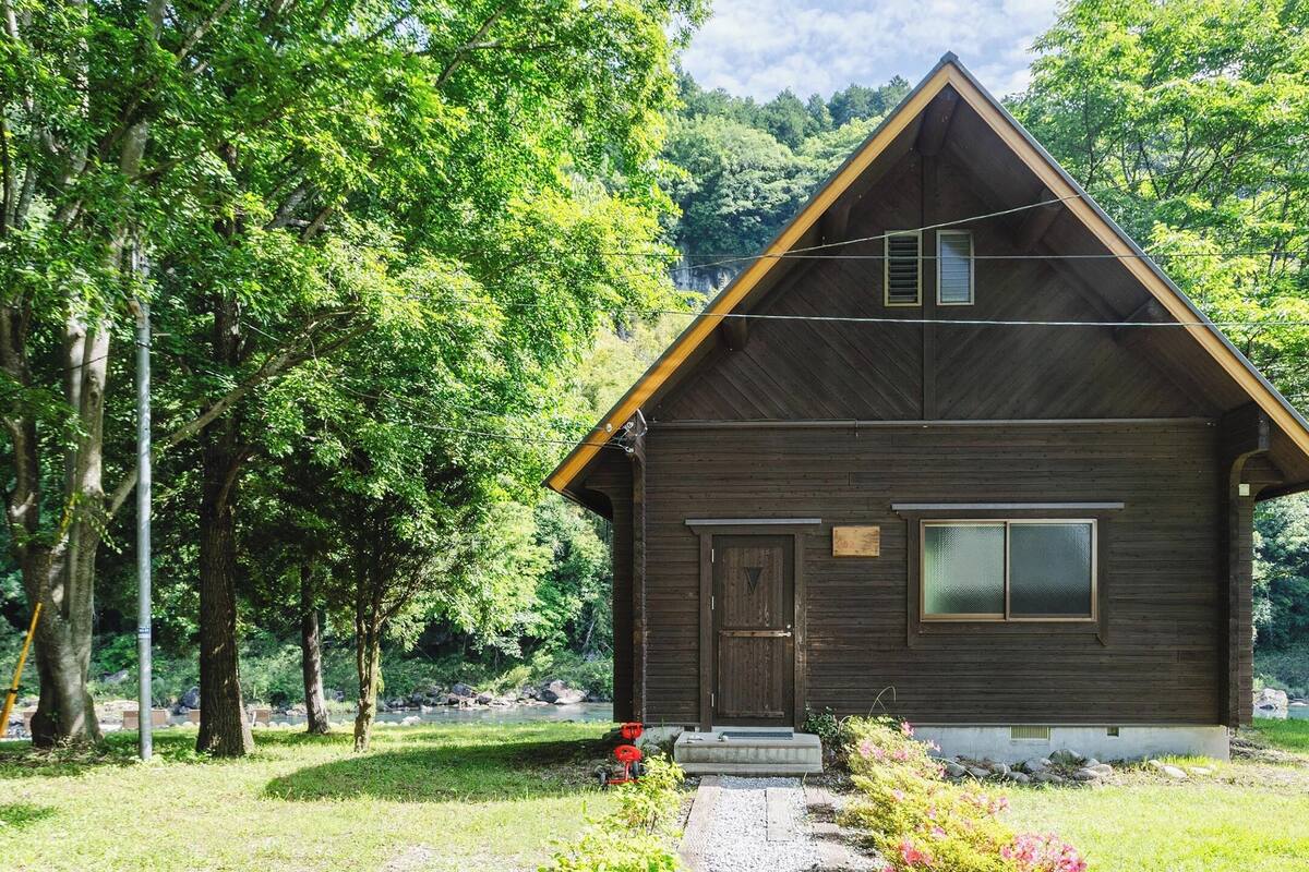 Une petite cabane en bois avec un toit à pignon, une porte d’entrée et une fenêtre.