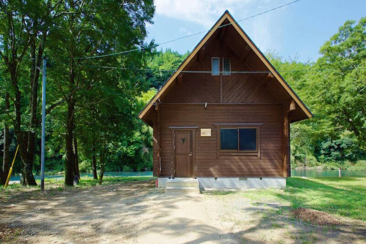 Une cabane en bois avec un toit à deux versants, une porte d’entrée et une petite fenêtre.