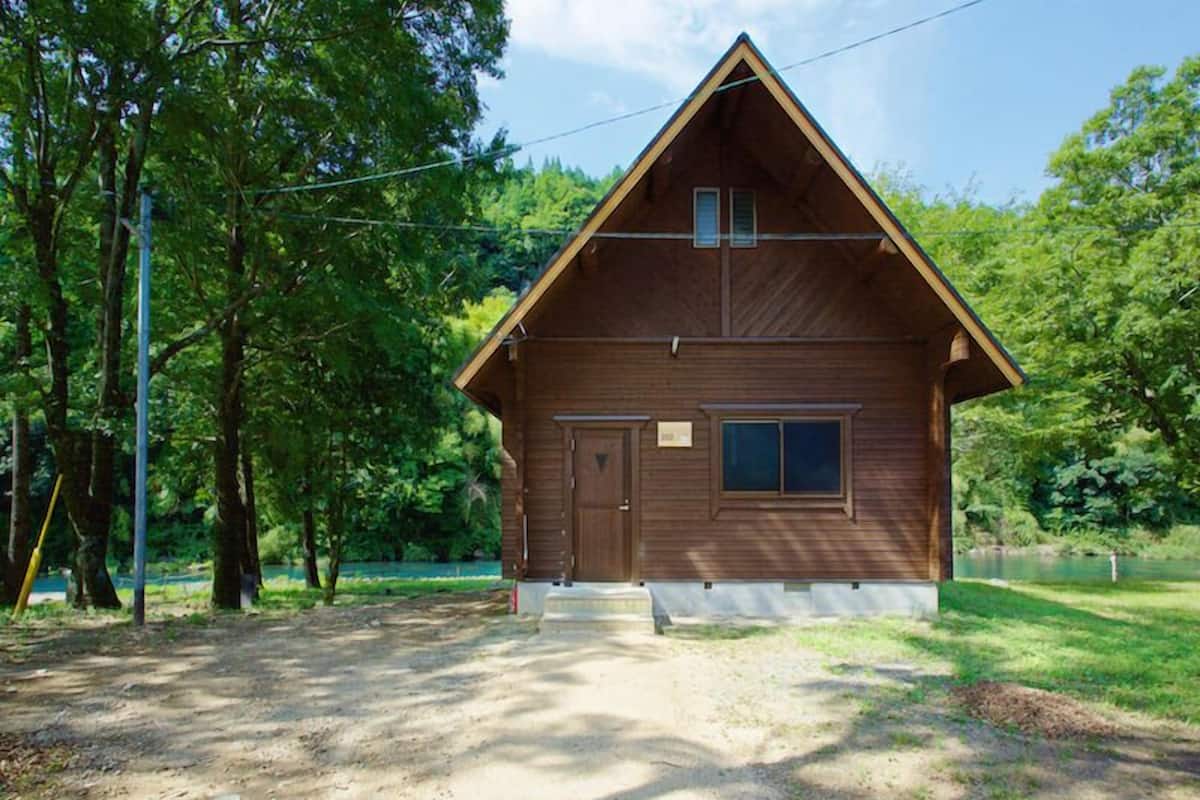 A wooden cabin with a pitched roof, a front door, and a small window.