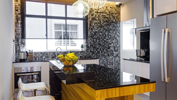 A modern kitchen with a central island, stainless steel appliances, and a large window providing natural light. - Shamrock Beach Villas 12 (George Town)