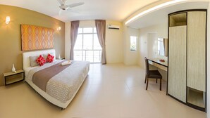 A modern hotel room with a large bed, a desk, and a wardrobe. - Shamrock Beach Villas 12 (George Town)