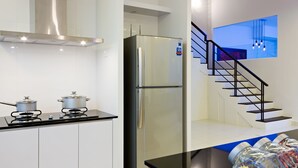 A modern kitchen with a stainless steel refrigerator, a gas stove, and a black countertop. - Shamrock Beach Villas 12 (George Town)