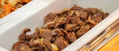 A white rectangular serving dish filled with cooked beef and onions.