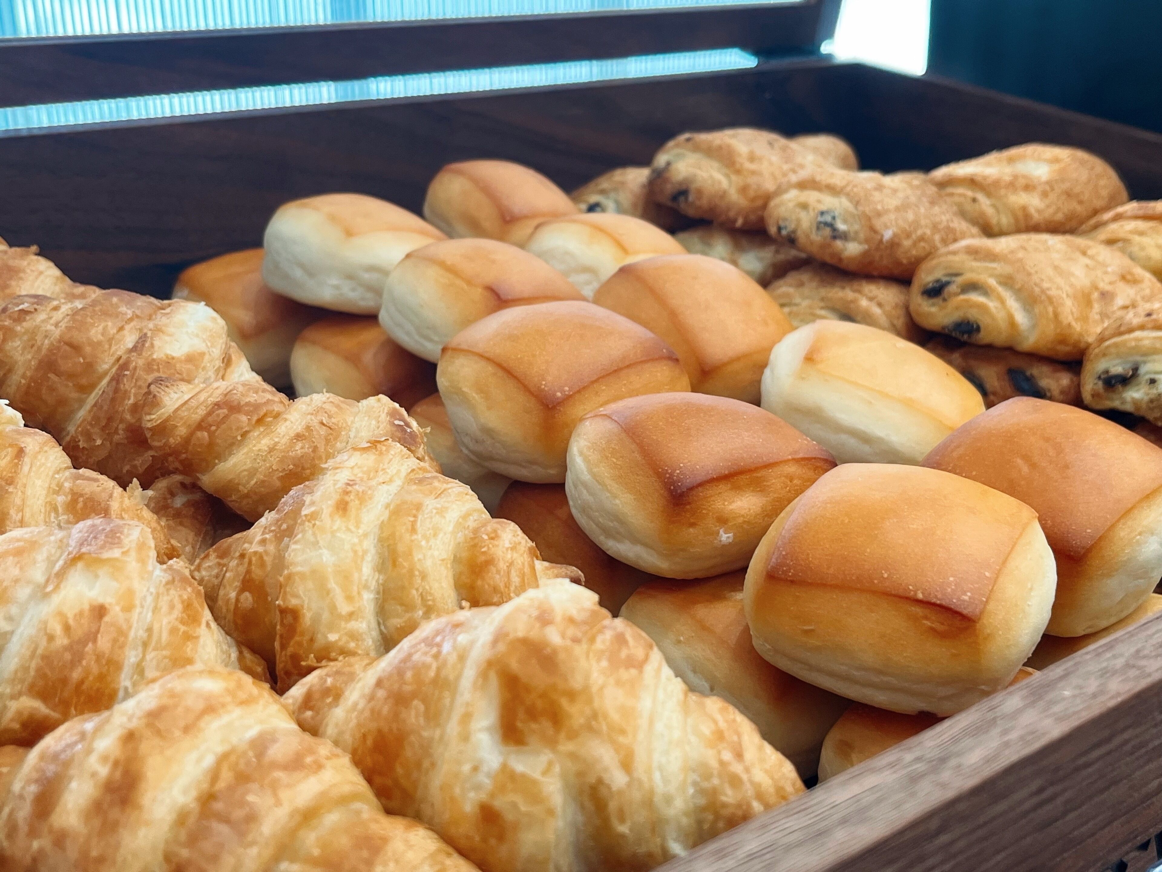 A tray of assorted baked goods including croissants and rolls.