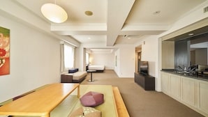 A modern hotel room with a wooden dining table, a sofa, a TV, and a kitchenette. - HOTEL GLOBAL VIEW SAPPORO (Sapporo)