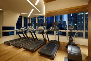 A gym with treadmills, an elliptical, and exercise bikes, large windows with a city view, and modern lighting. - LOTTE CITY HOTEL MYEONGDONG (Seoul)