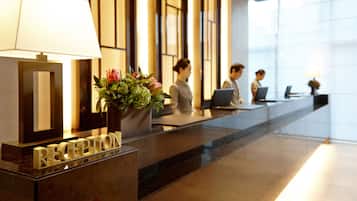 A reception desk with a lamp, a potted plant, and a sign that reads "RECEPTION".