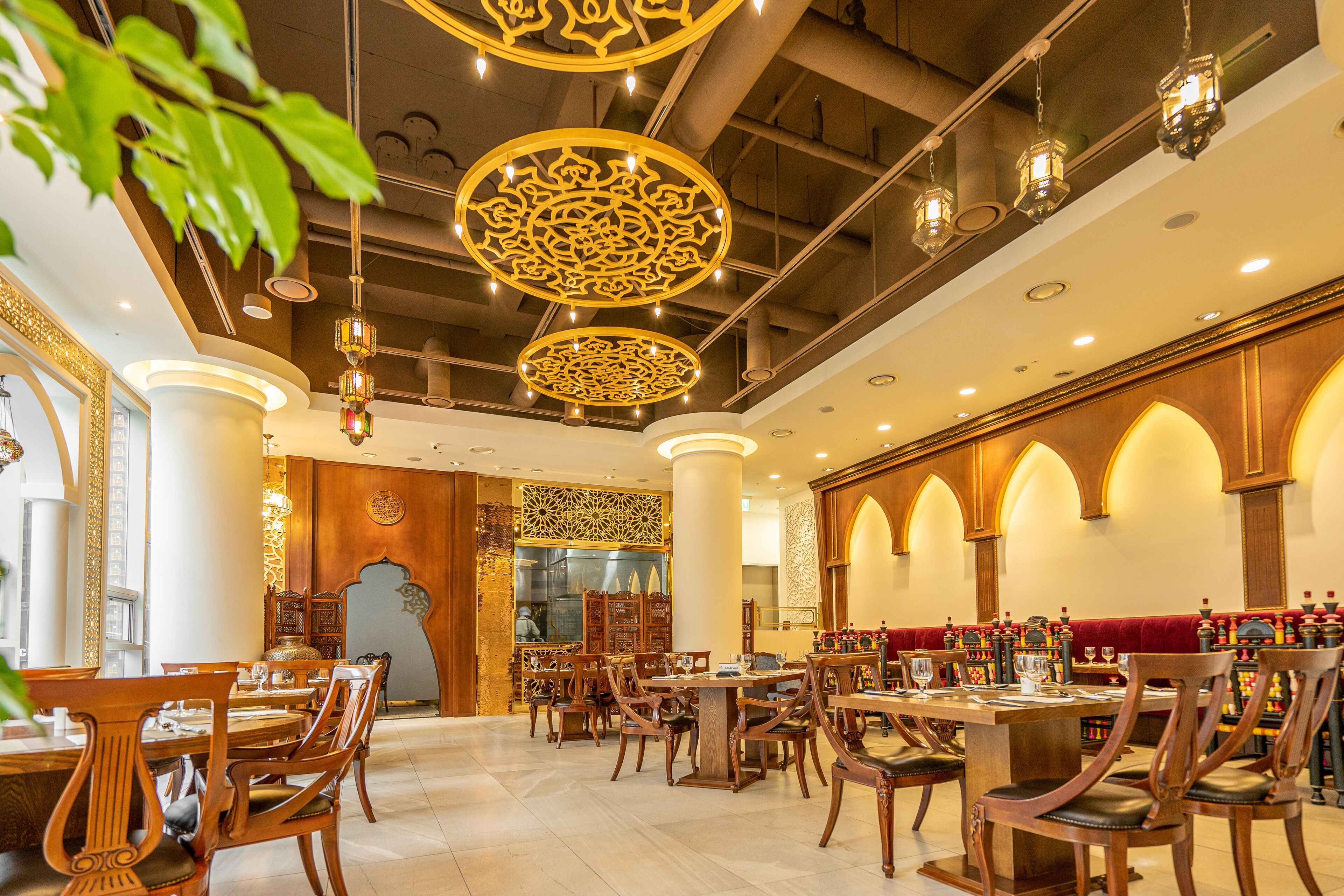 A restaurant with wooden tables and chairs, ornate ceiling decorations, and a warm ambiance.